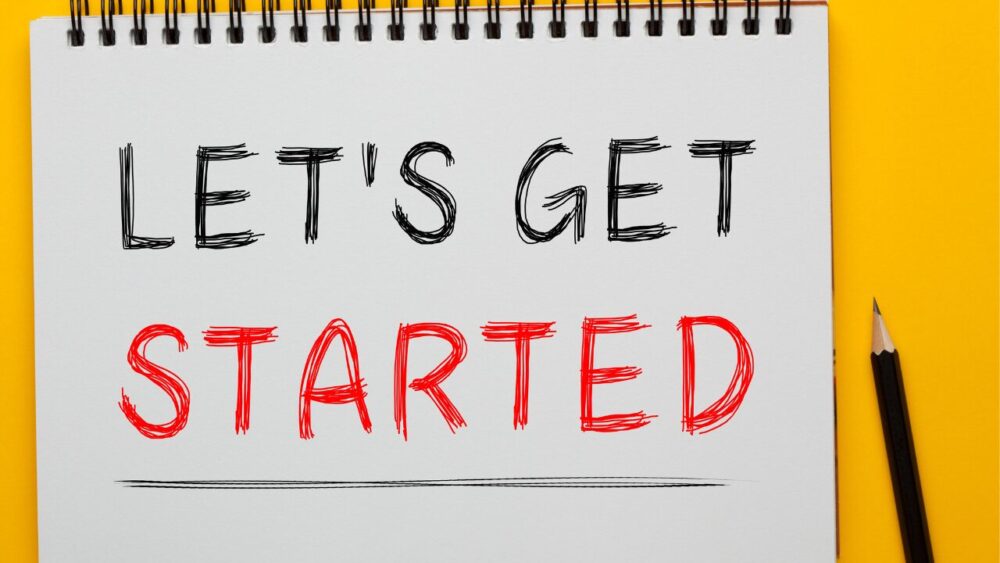 手書きの文字で「LET'S GET STARTED」が書かれたノートと黄色い背景上の鉛筆の画像。動機付けと新しい始まりのコンセプトを表現。