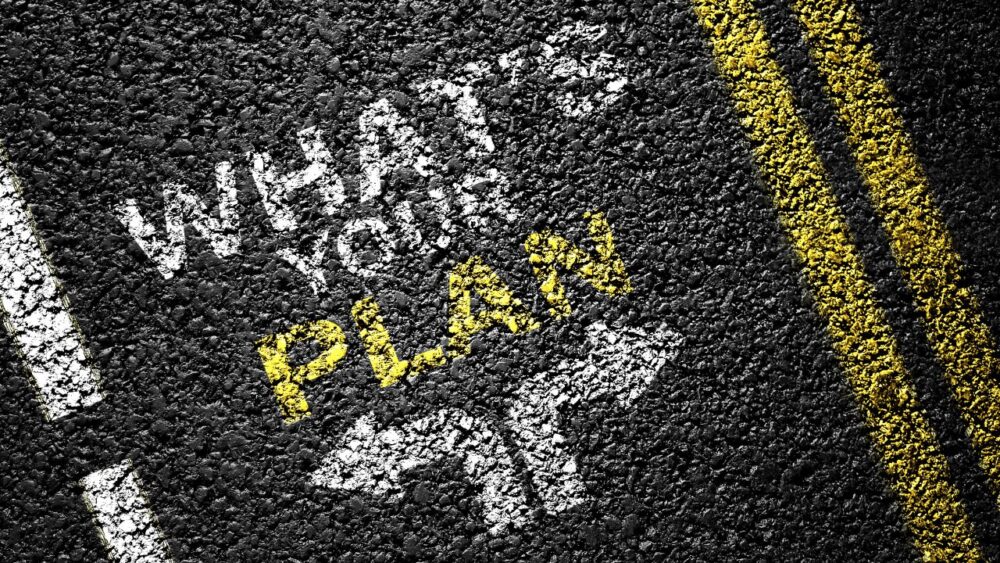 アスファルトの道路に 'WHAT'S YOUR PLAN' と書かれたメッセージと分岐する矢印のイラスト
